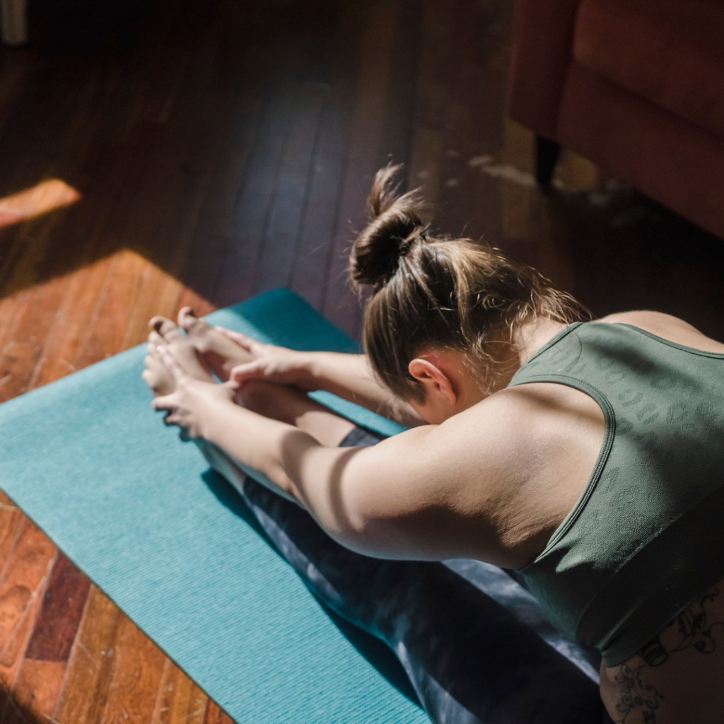 womand sitting on a ygoa mat stretching