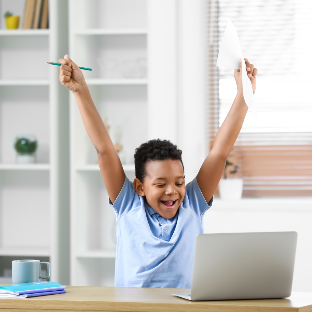 young boy celebrating school work on the computer