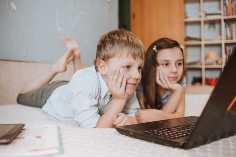 The boy and girl watching webinar on laptop at home during CoVid-19 quarantine, distance learning online with a laptop, a child doing homework for school. Children stayed at home. Home education
