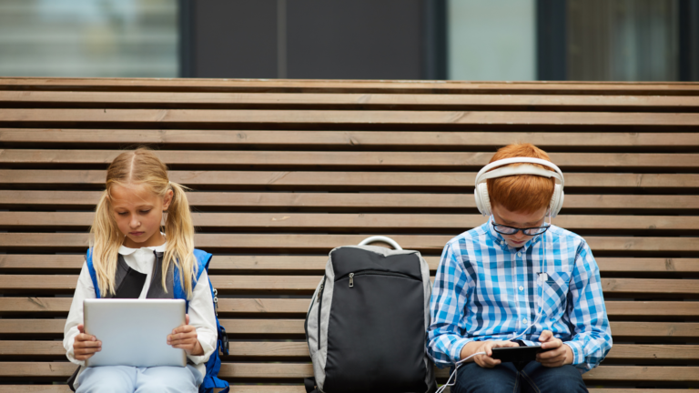 two children on a bench loking at their phones