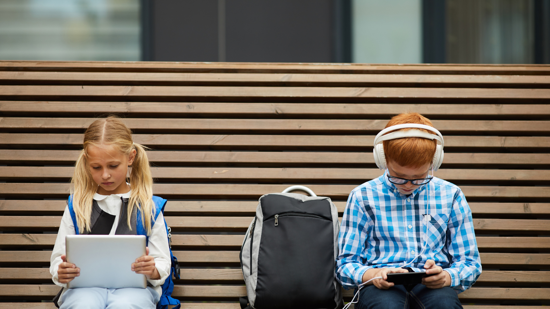 two children on a bench loking at their phones