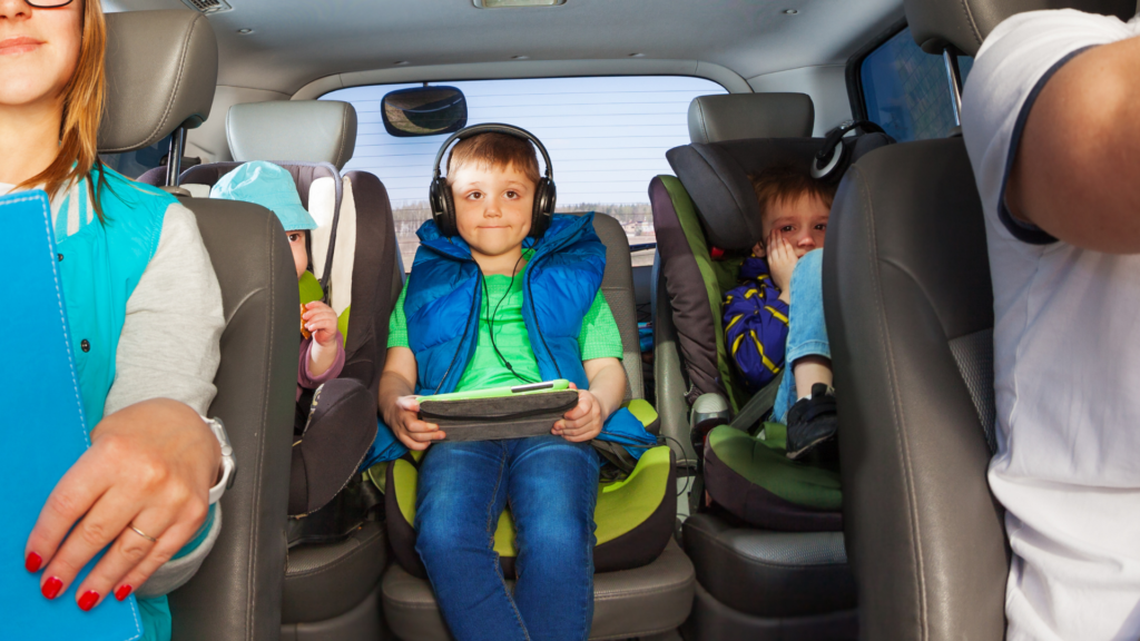 little boy in car with electronic with his family