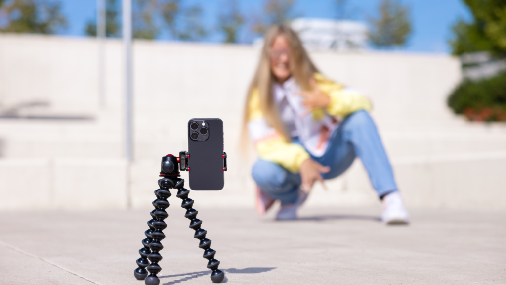 a young girl taking a remote phone from her phone on a tripod